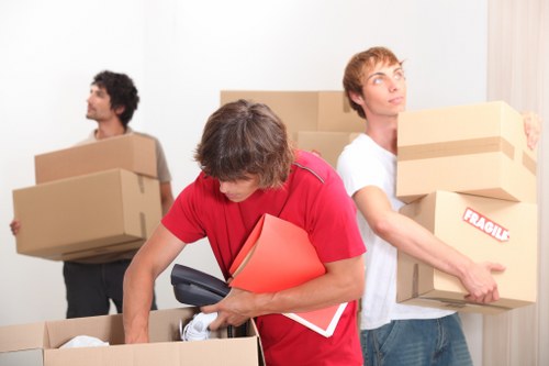 Movers handling boxes and furniture in a period property with stairs and narrow access